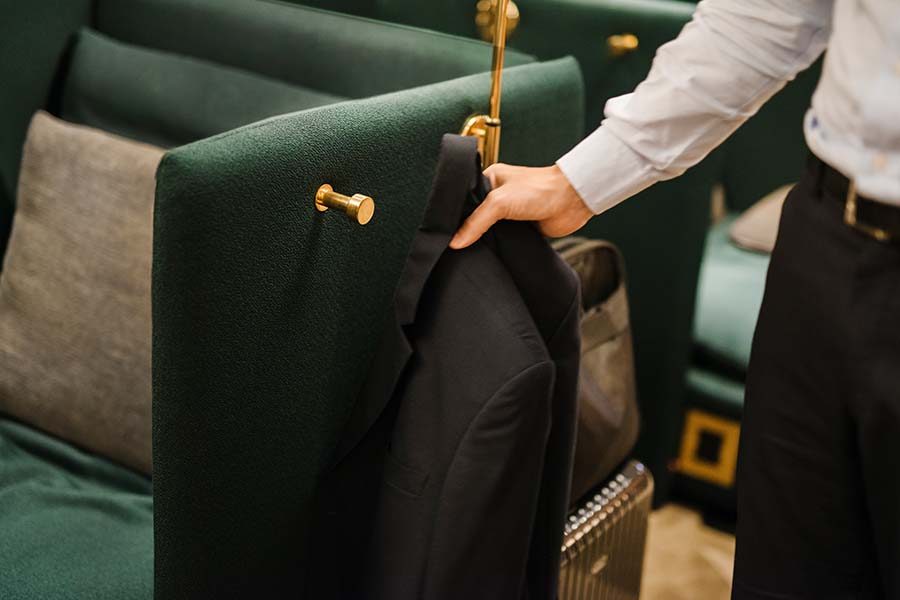 Blazer being hung on coat hook on the side of a lounge chair